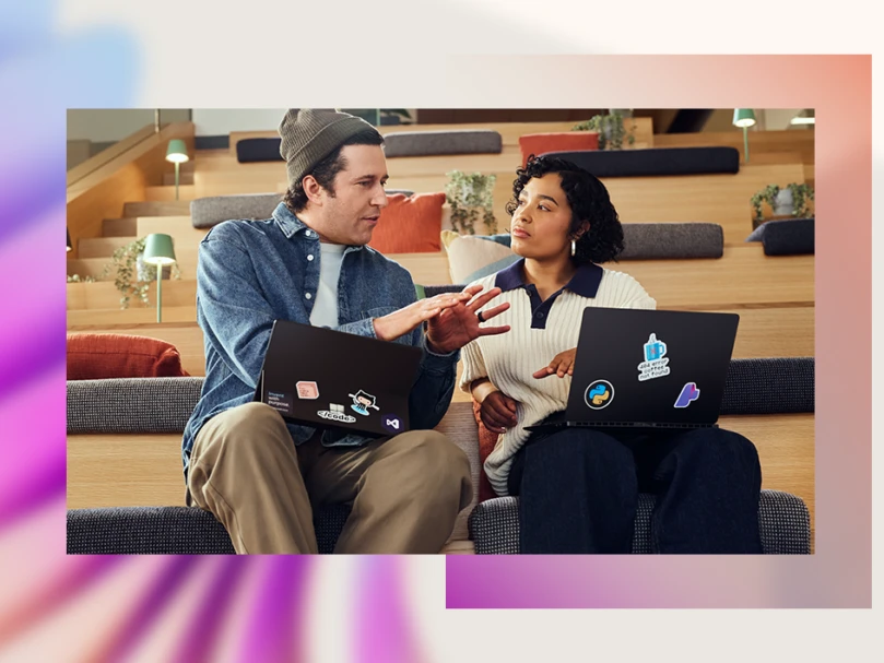 A man and woman sitting on stairs with laptops