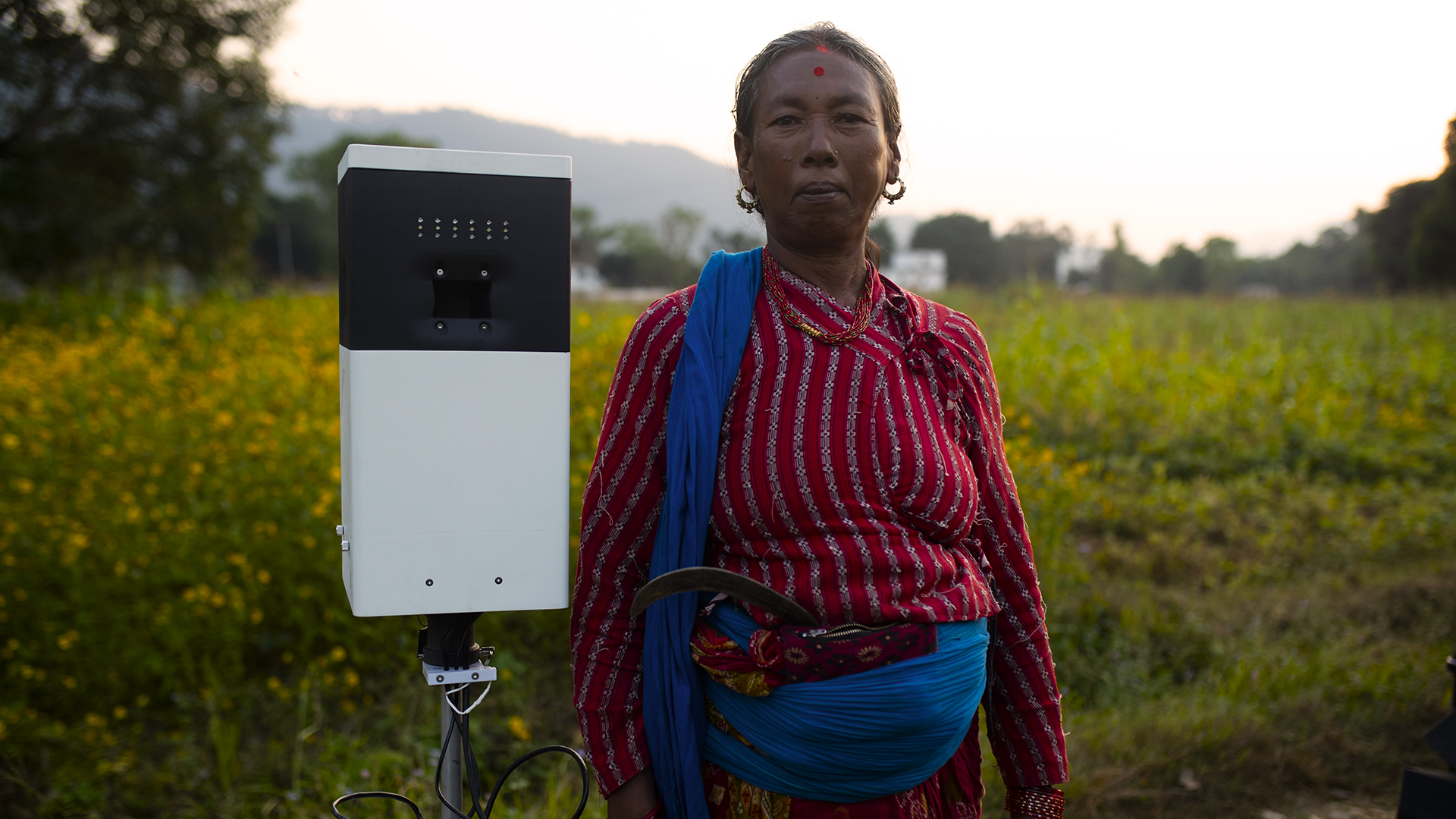photo of a Nepalese woman standing next to a biological weather station